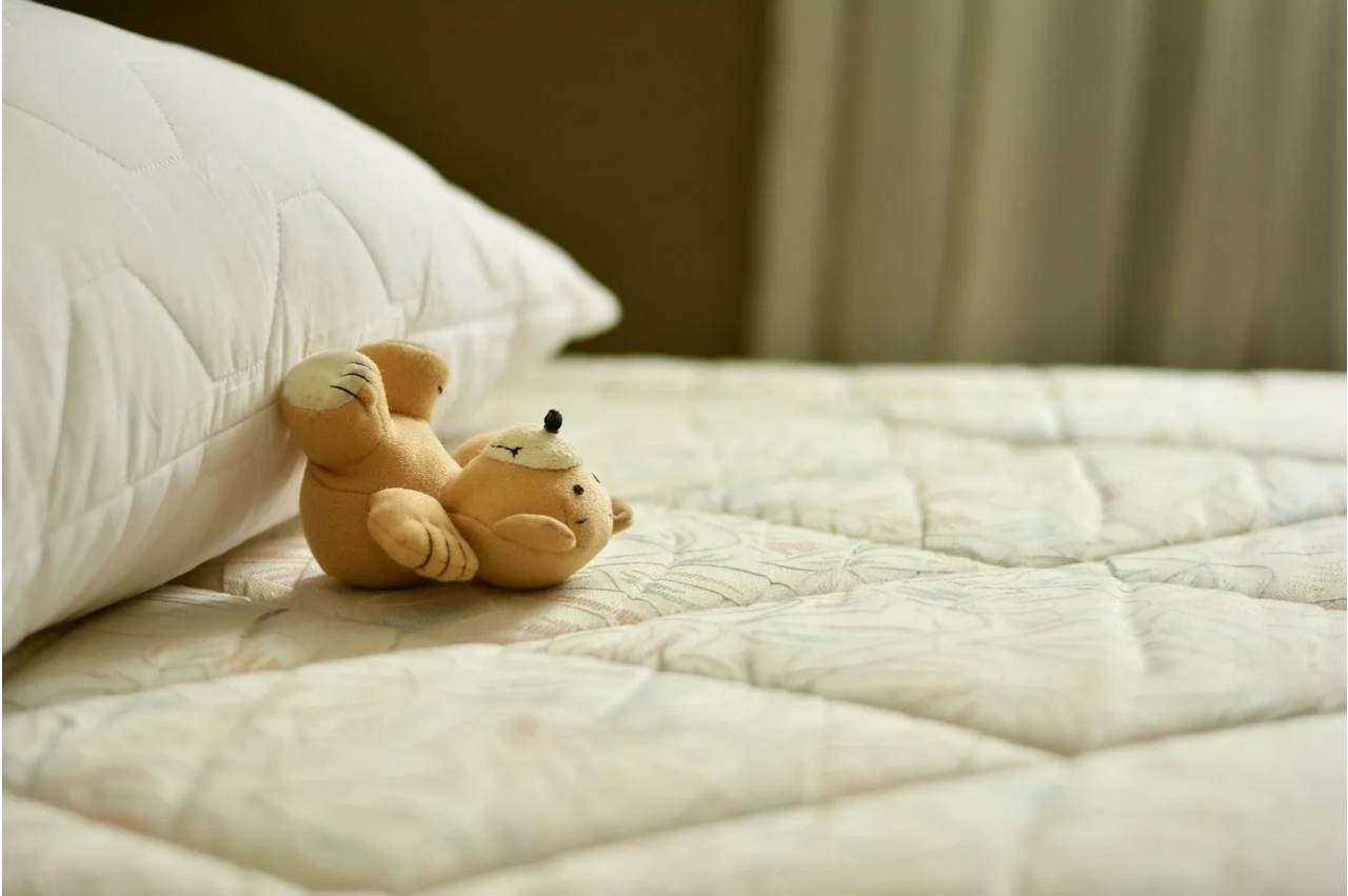 White pillow and soft toy on bed.